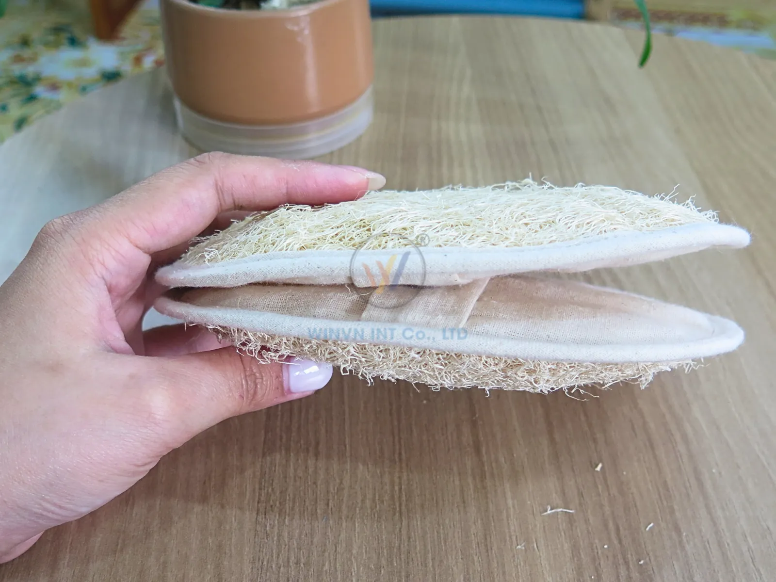 Side view of an oval loofah exfoliating pad showing fibre thickness and fabric edge binding